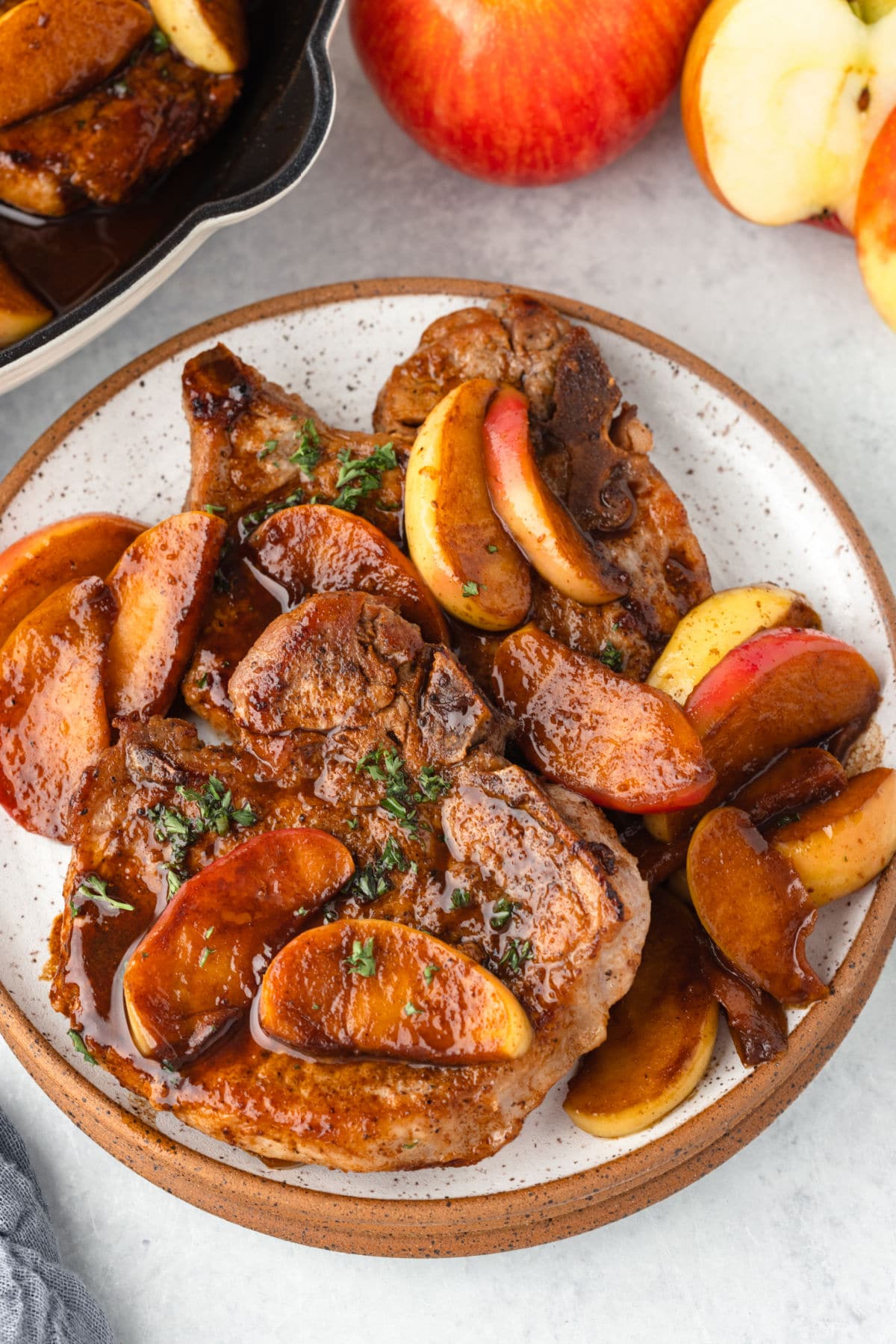 Pork chops and apples on a plate next to fresh apples.