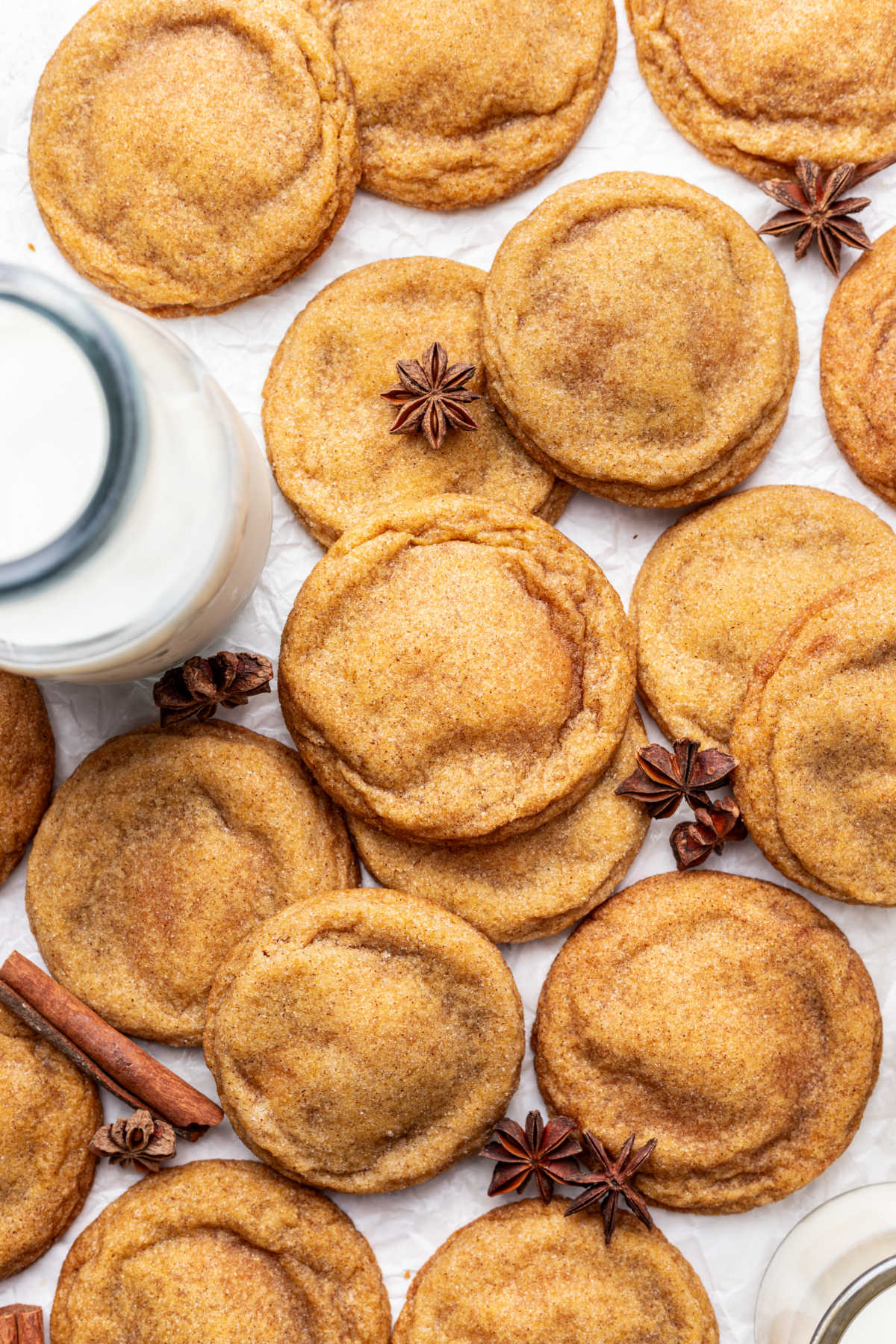 Overlapping pumpkin cheesecake cookies next to carafe of milk.