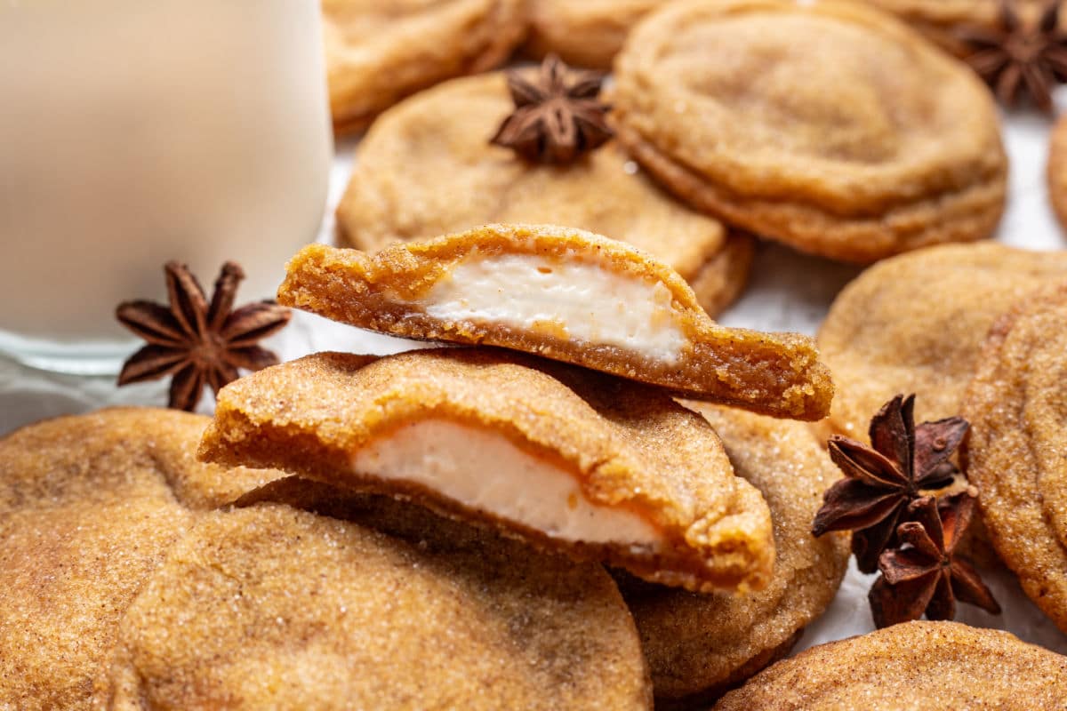 A pumpkin cheesecake cookie in half on top of other pumpkin cheesecake cookies.