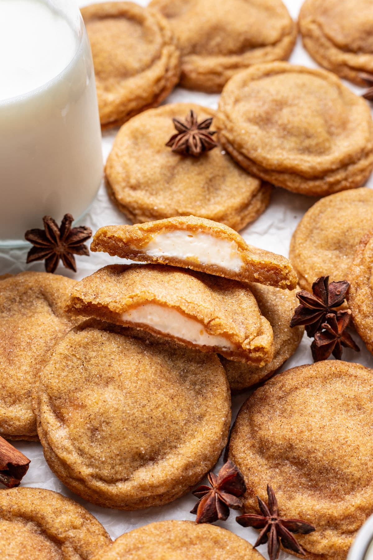 A pumpkin cheesecake cookie broken in half next to more overlapping cookies.