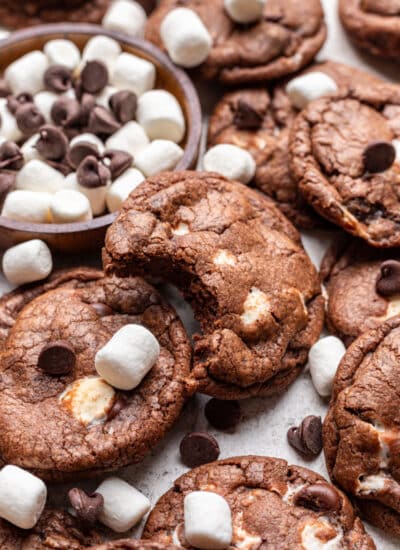A chocolate marshmallow cookies with a bite missing overlapping more cookies.