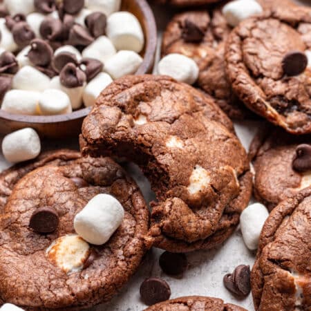 A chocolate marshmallow cookies with a bite missing overlapping more cookies.