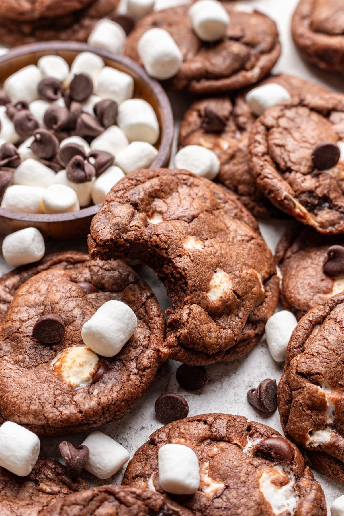 A chocolate marshmallow cookies with a bite missing overlapping more cookies.