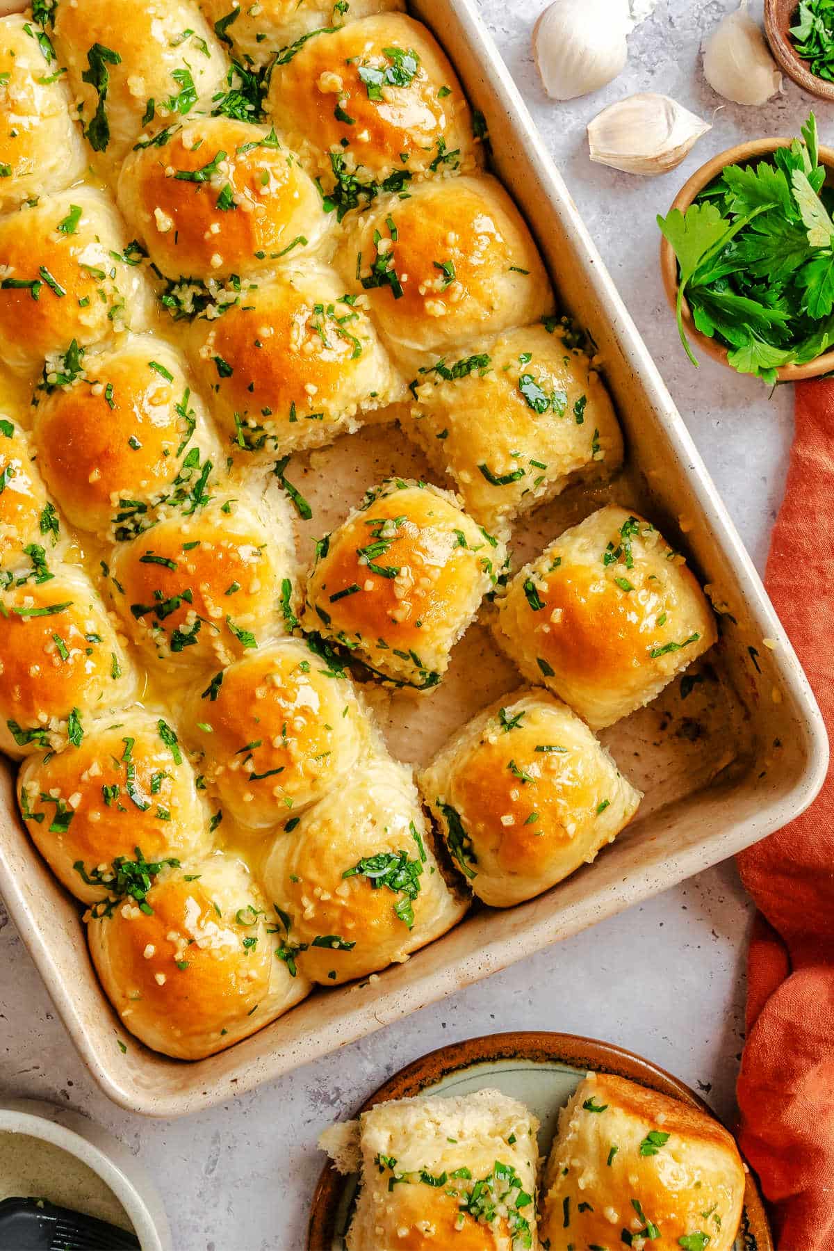 Garlic butter dinner rolls at an angle in a baking pan.