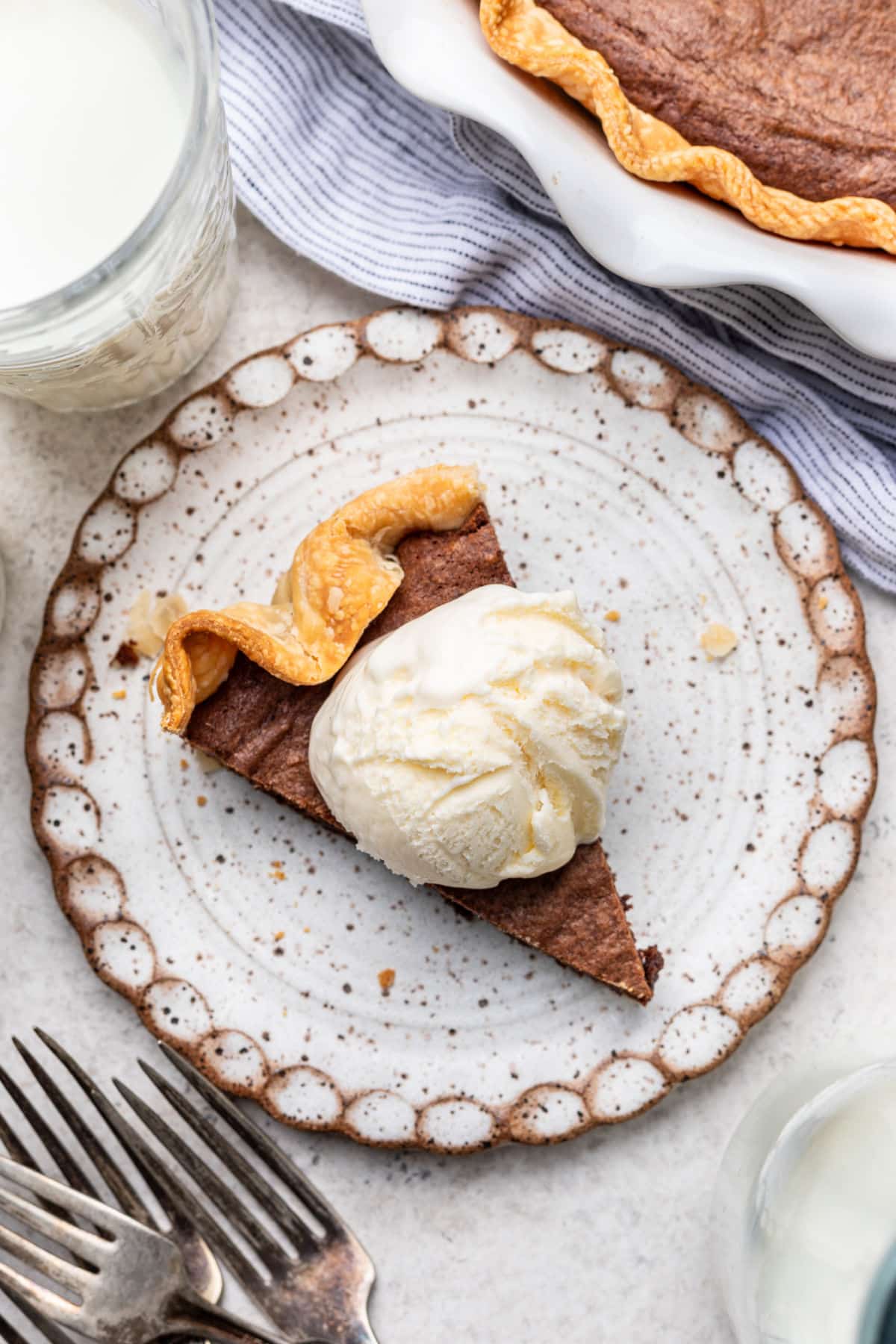 A slice of brownie pie topped with a scoop of vanilla ice cream.