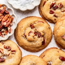 Butter pecan cookies overlapping next to a dish of salt.