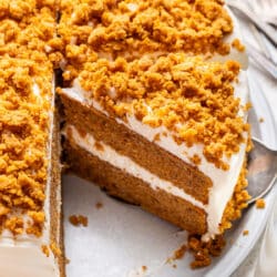 A slice of pumpkin layer cake next to the rest of the cake.