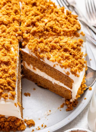 A slice of pumpkin layer cake next to the rest of the cake.
