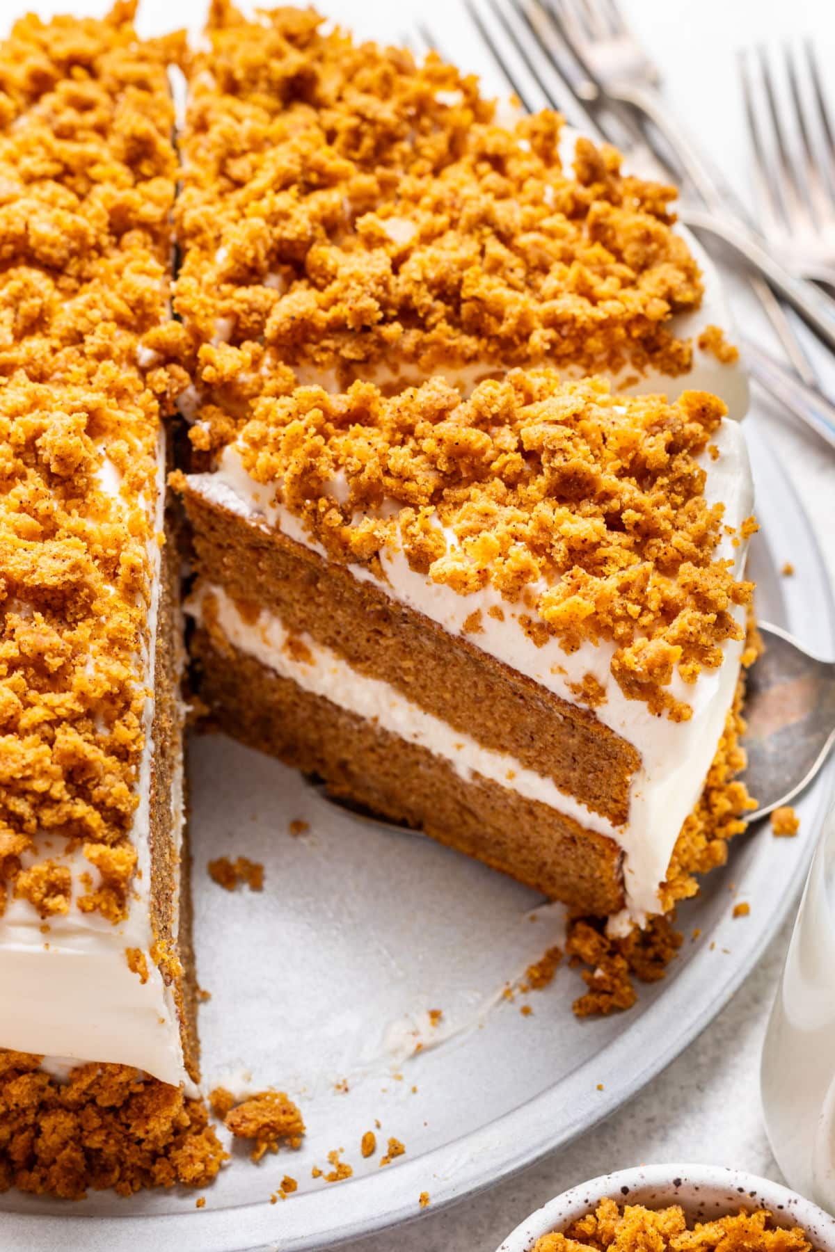 A slice of pumpkin layer cake next to the rest of the cake.
