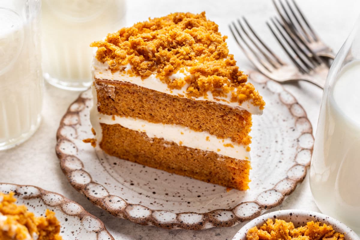 a slice of pumpkin layer cake on a plate next to three forks.
