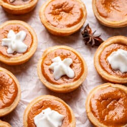 A row of mini pumpkin pies part with a star of whipped cream on them.