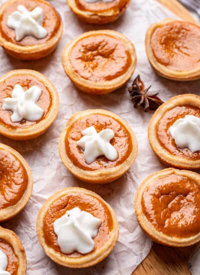 A row of mini pumpkin pies part with a star of whipped cream on them.