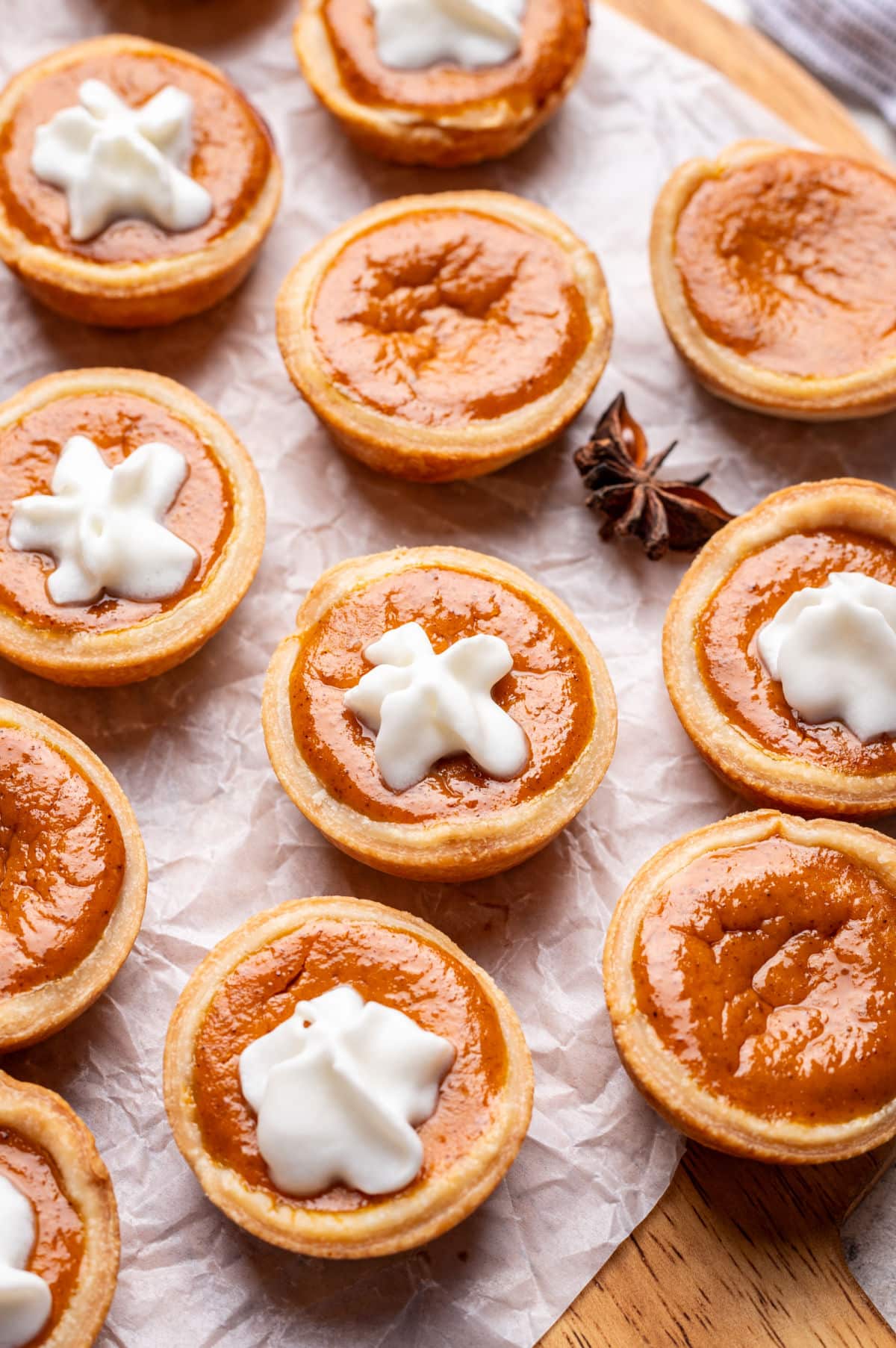 A row of mini pumpkin pies part with a star of whipped cream on them.
