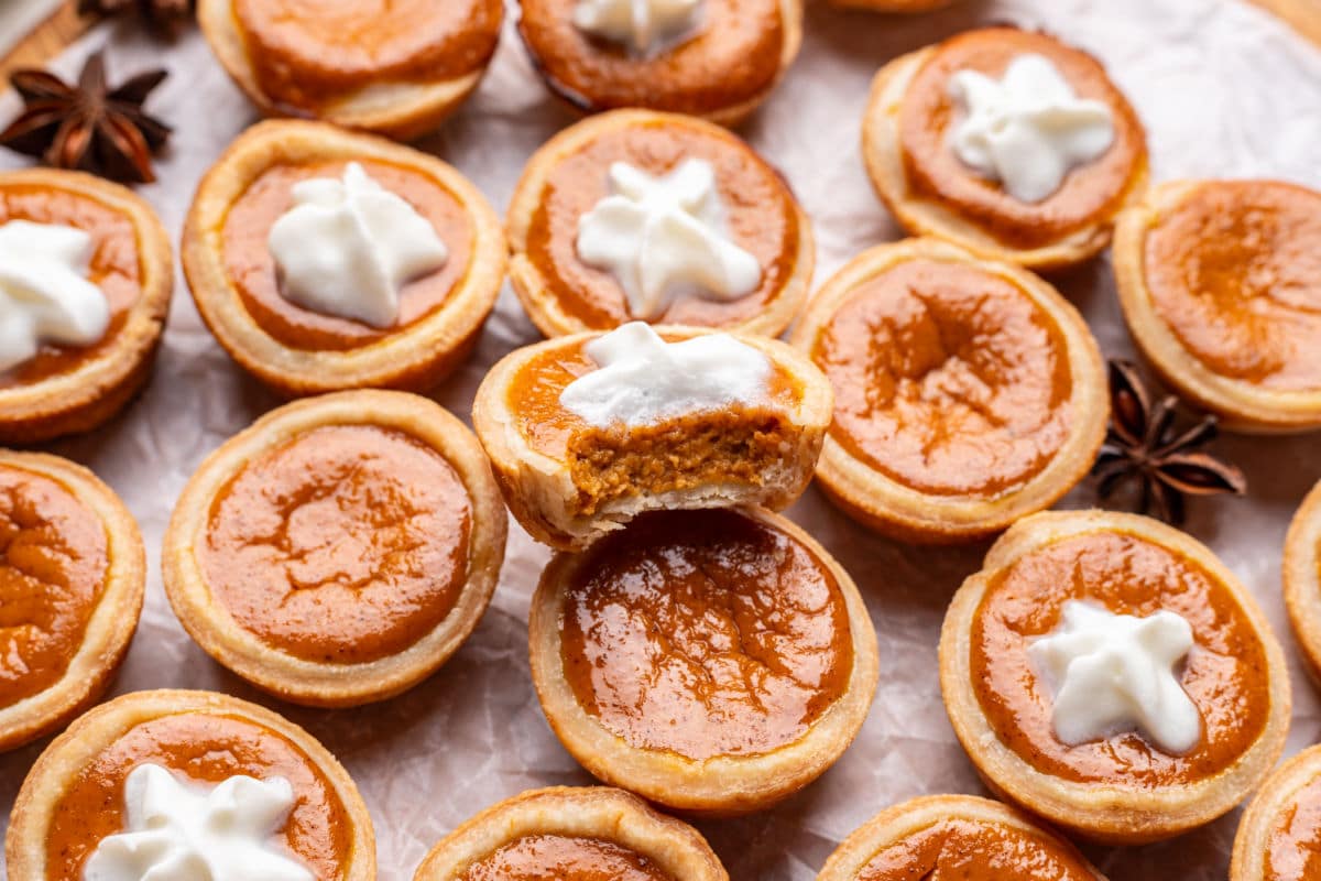 A pumpkin pie tassie with a bite missing on top of other tassies.